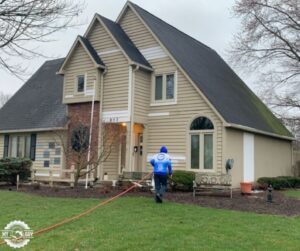 pressure washing technician carrying hose preparing to clean house exterior